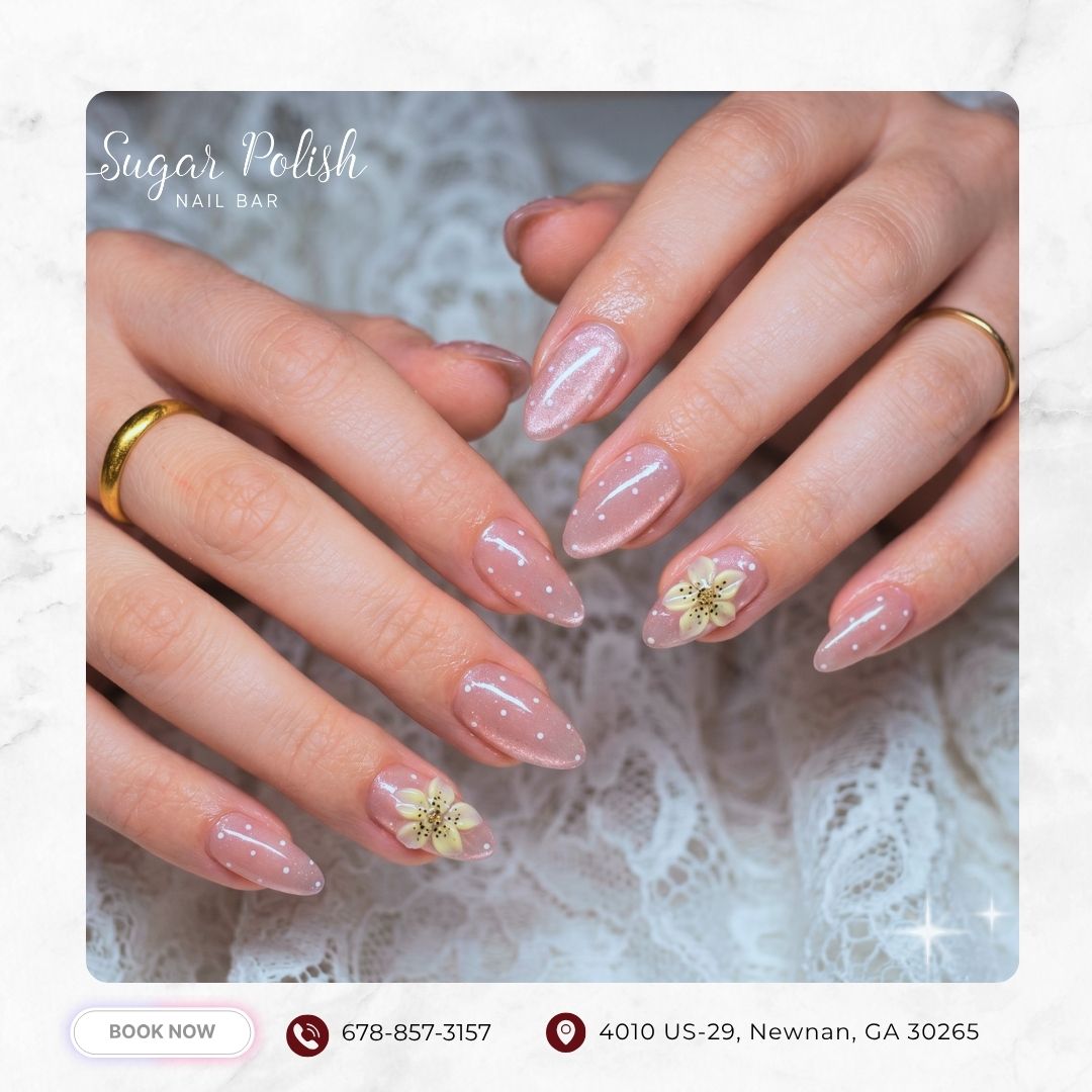 Glossy nude almond nails with delicate floral accents and soft feminine details