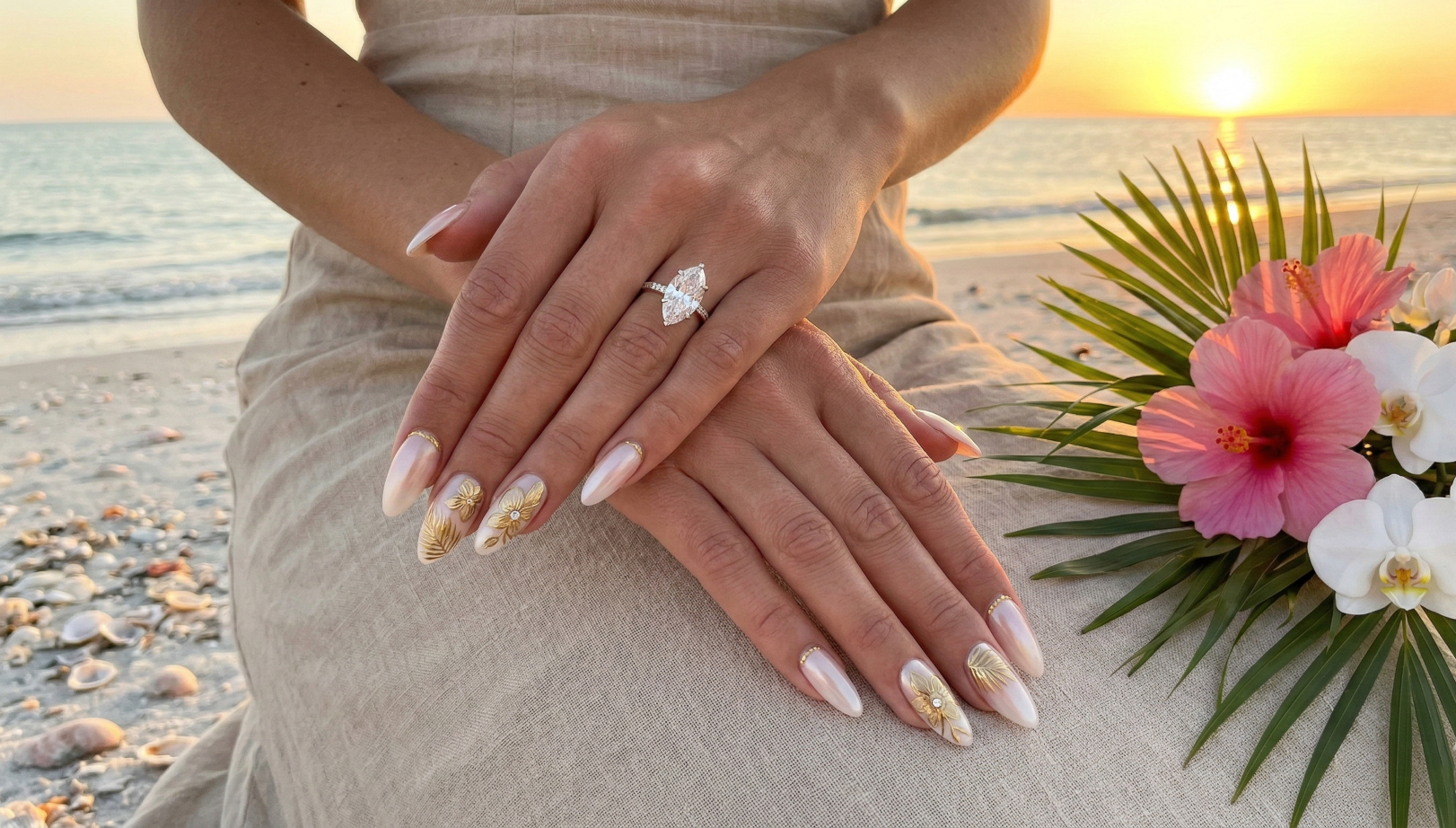 Elegant almond-shaped pearl chrome nails with gold tropical leaf and floral accents, perfect for a beach wedding, at Sugar Polish Nail Bar in Newnan GA