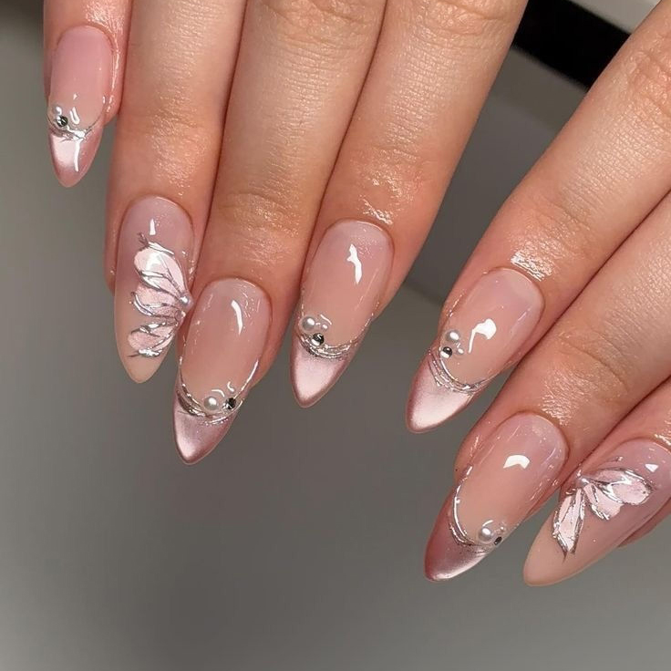 Soft pink chrome nails with 3D silver butterfly wing outlines, pearl accents, and almond shape