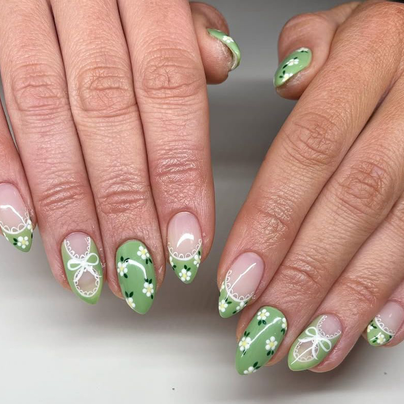 Sage green almond nails with white daisy patterns and lace bow nail art