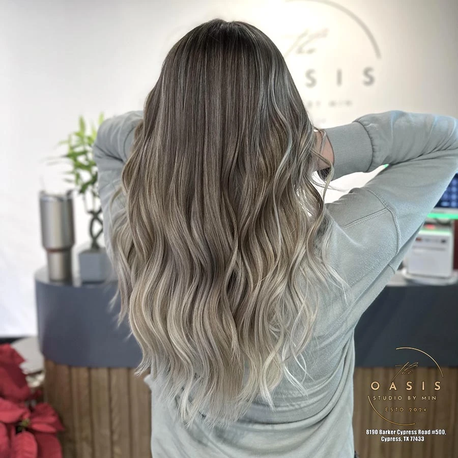 Ash blonde balayage & seamless highlights on a dark base with glamorous loose curls.