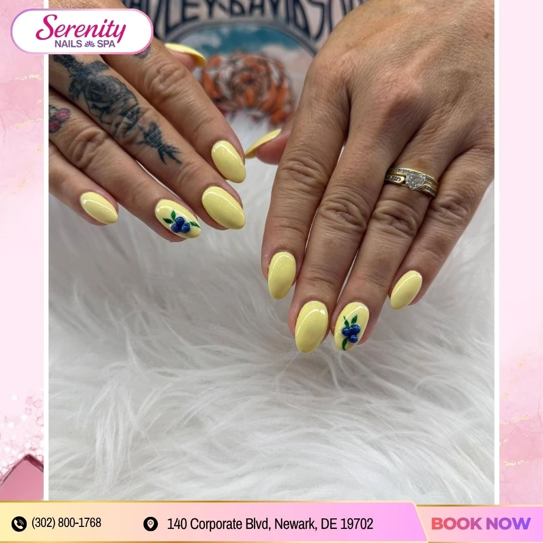 Glossy yellow almond nails with a blueberry accent design at Serenity Nails & Spa